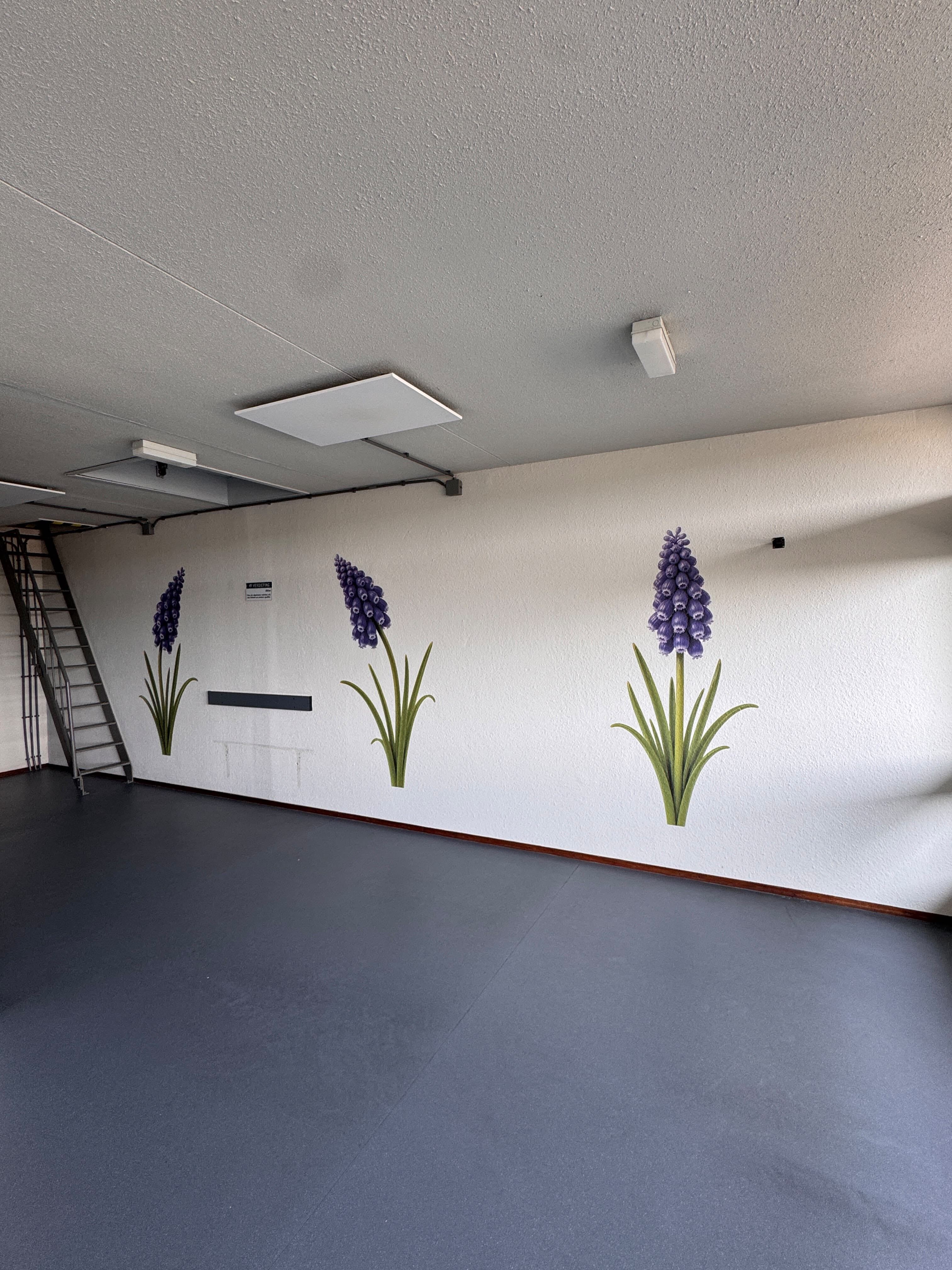 Paarse bloemen als muurprint op een lange wand in een hal van Elkien